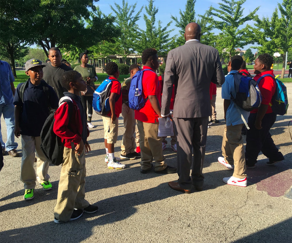 Administrator at Carter G. Woodson Elementary greeting students as they enter school building